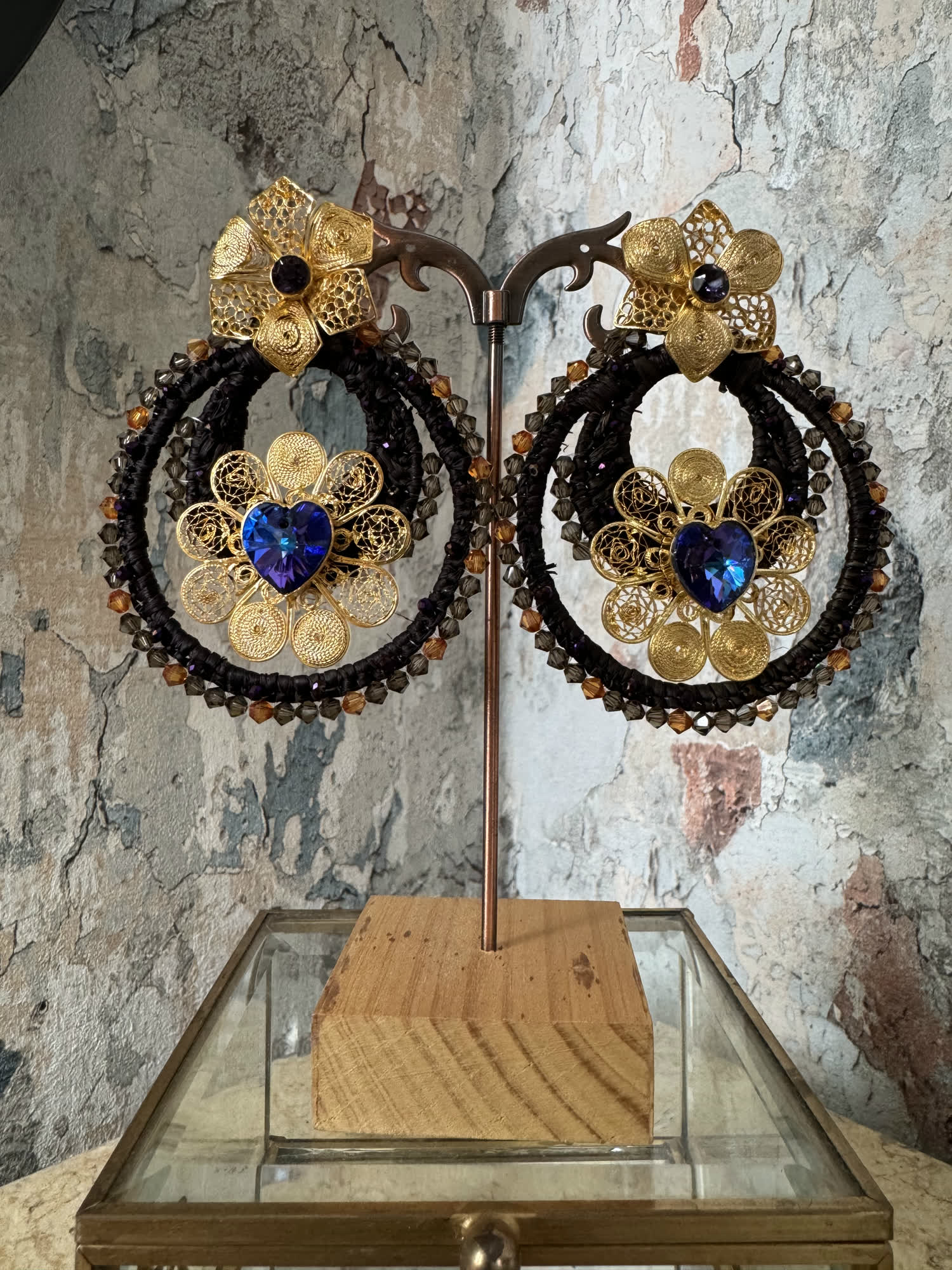 Aretes negros circulares con filigrana dorada y corazón de cristal azul