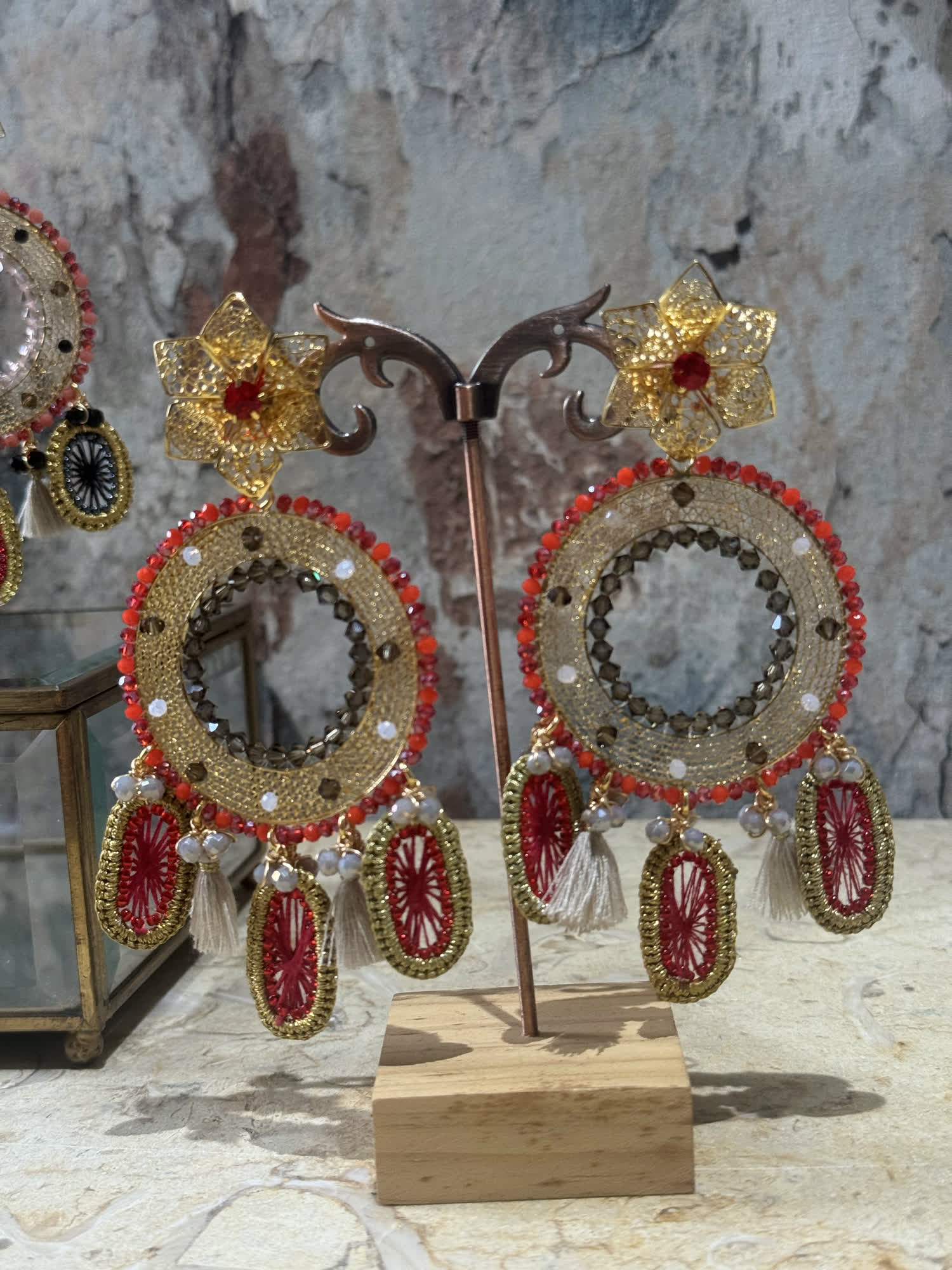 Aretes circulares rojos y dorados con borlas blancas y flor de filigrana