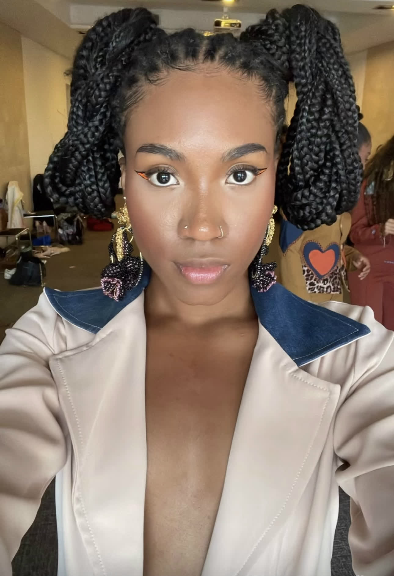 Modelo en backstage con aretes de la marca y chaqueta de denim
