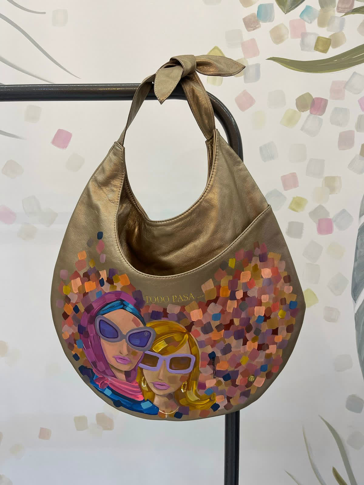 Bolso de cuero dorado pintado a mano con dos mujeres con gafas de sol y la frase Todo Pasa