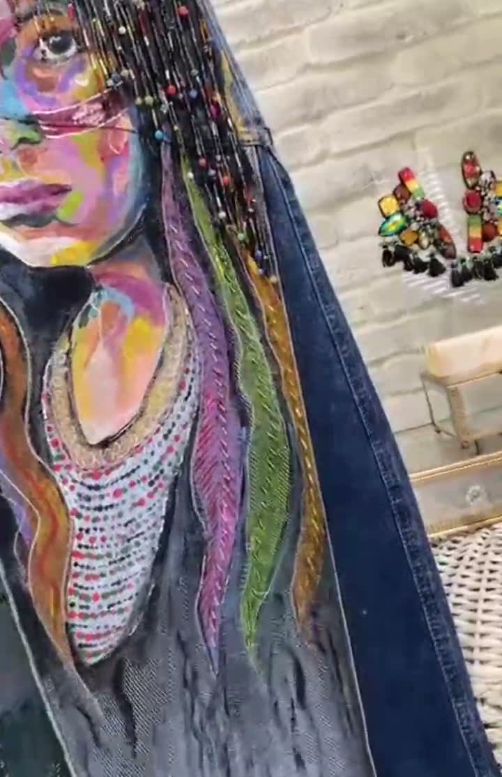 Rostro pintado a mano sobre denim con el cabello bordado en cientos de mostacillas de colores