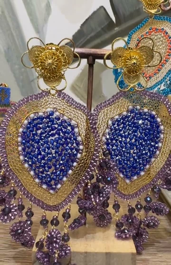 Aretes Los Luana: corazón de cristal azul rodeado de malla dorada y racimos violeta, sobre flor de filigrana